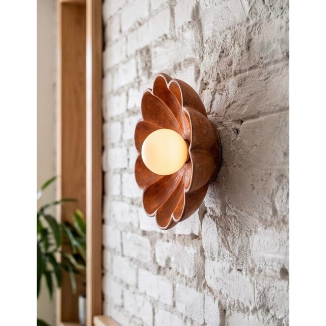 Bring warmth and character to any wall with this flower wall sconce, hand-carved from natural red travertine. Soft,...