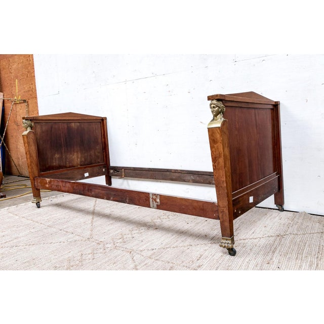 An early 19th century French Empire burl mahogany daybed with equal height headboard and footboard, plain paneled backs,...