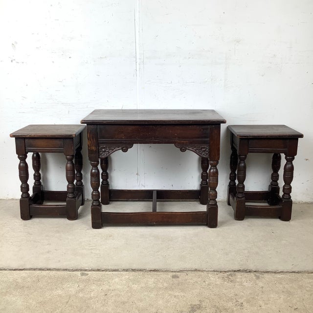 This vintage set of three nesting tables reflects the enduring appeal of Tudor and Jacobean revival design, rendered in a...