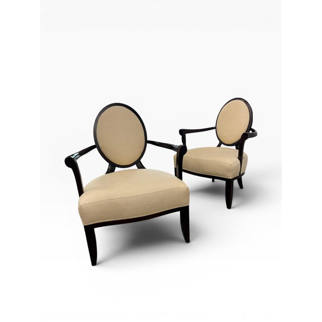 A refined pair of Baker Furniture lounge chairs showcasing a graceful barrel-back silhouette with distinctive oval...