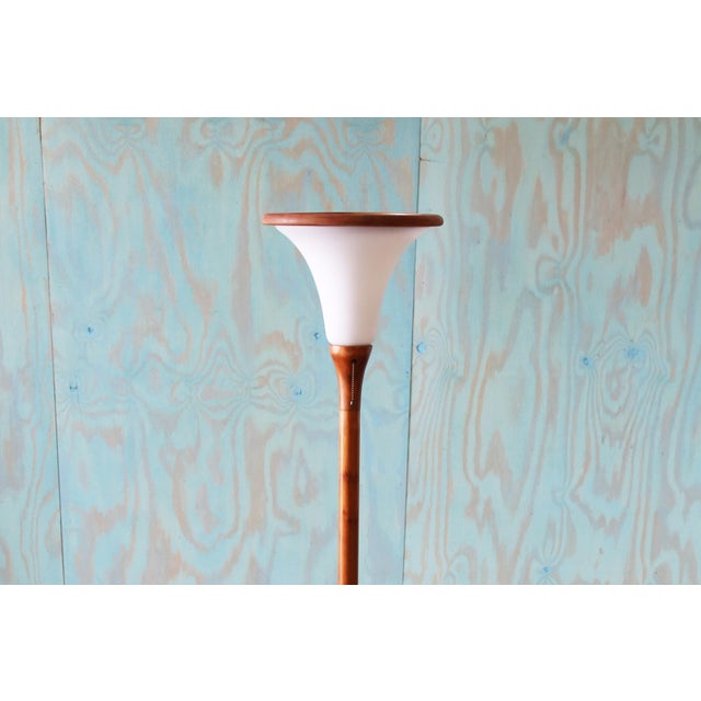 A danish modern solid teak floor lamp featuring a thick stem culminating in a tulip shaped frosted glass shade. the glass...