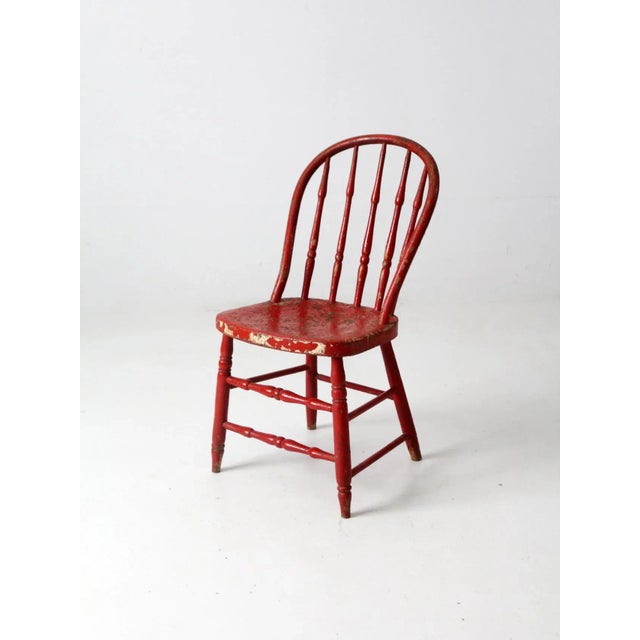 This is an antique bow back Winsdor chair. The classic red farmhouse dining chair has a turned spindle back.
