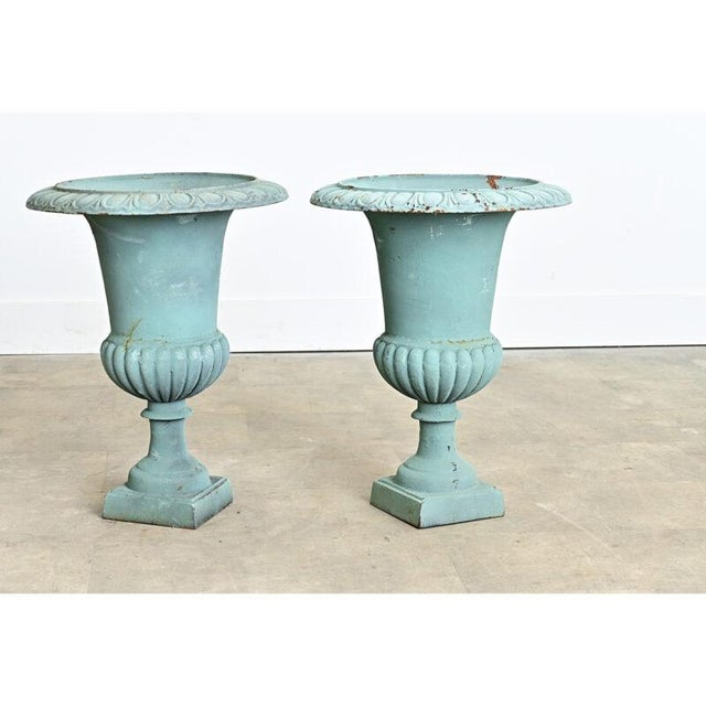 An elegant pair of late 19th century French cast iron garden urns which display a Neoclassical taste in their profile,...