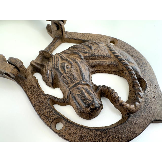 Vintage cast iron door knocker featuring a detailed horse head within a classic horseshoe form. Finished in a weathered...