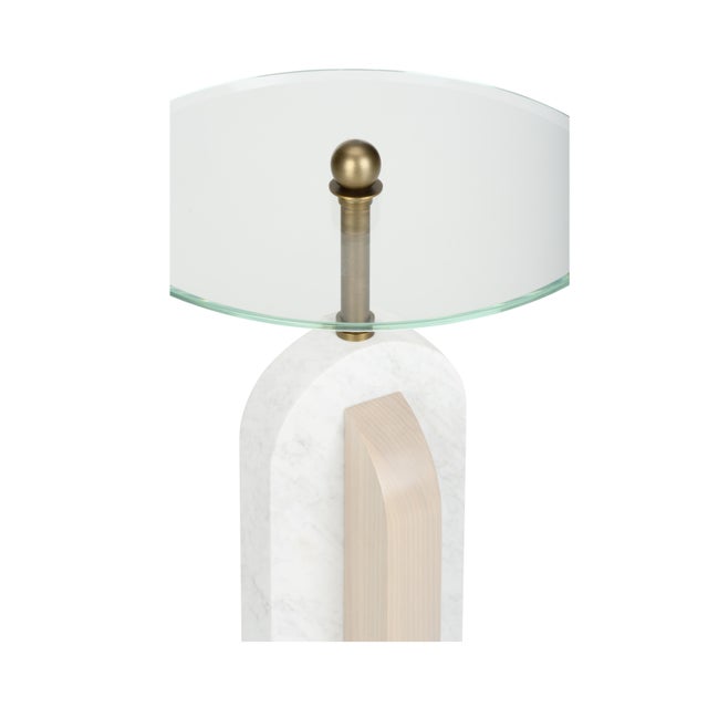 An antique brass base, neck and glass top highlight intersecting honed Carrera marble and rift-cut White Oak arches. The...