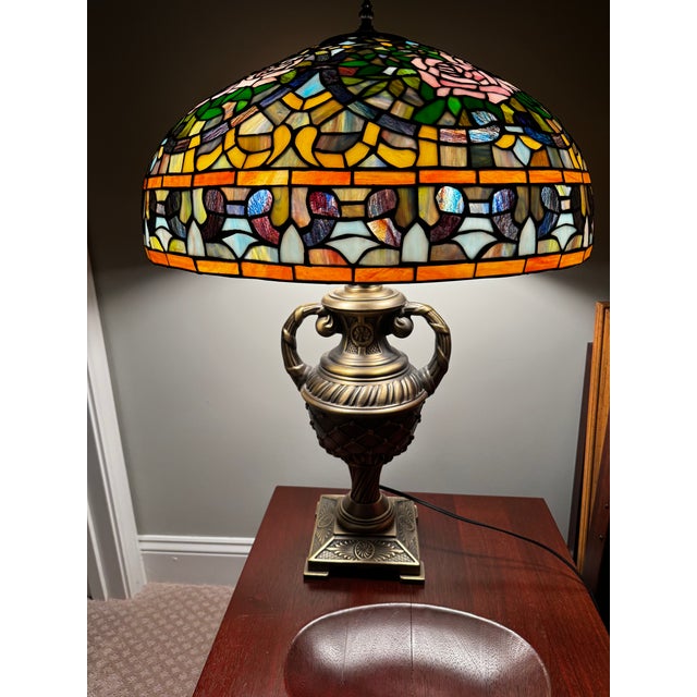 Tiffany style stained rose petal three (3) bulb stained glass table lamp with brass base. Lamp shade has pink and pearl...