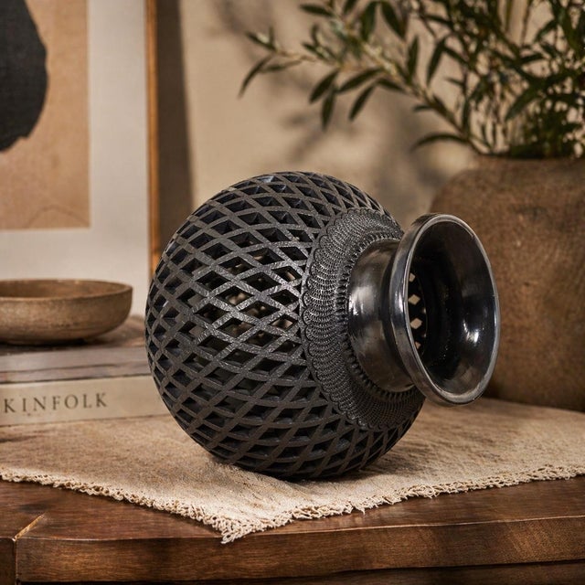 A striking example of traditional barro negro pottery from Oaxaca, Mexico, this hand-carved vessel features an intricate...