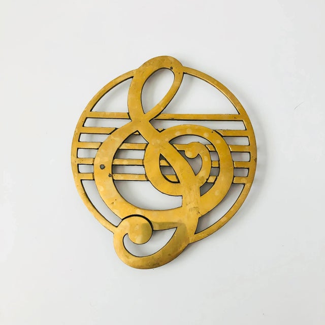 A vintage brass trivet with a treble clef design. Raised feet on the bottom. Perfect for keeping hot dishes off of...