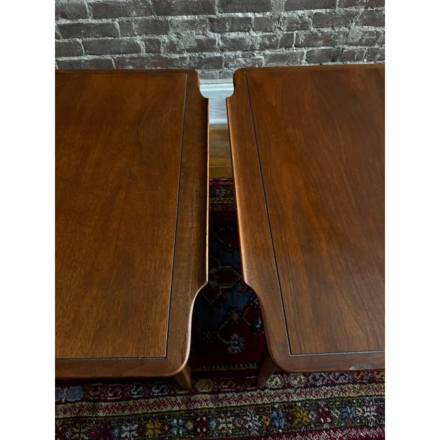 An absolutely gorgeous pair of vintage mid-century modern walnut end tables featuring elegant sculpted top edges, warm...
