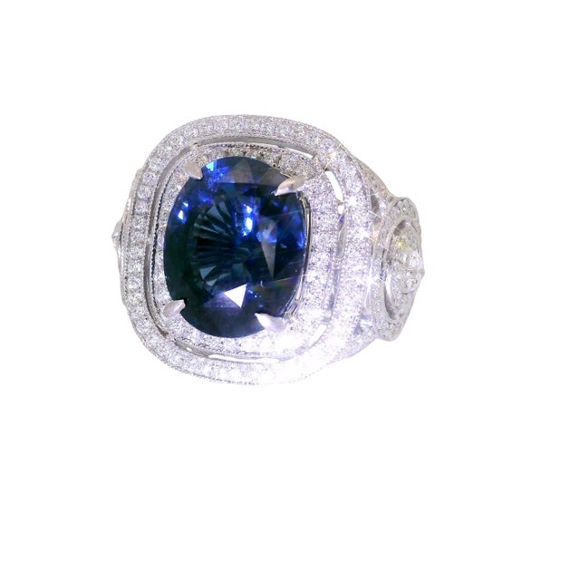 A captivating ring featuring a central blue spinel, cut in an elegant oval shape, weighing 5.79 carats. The deep blue hue...