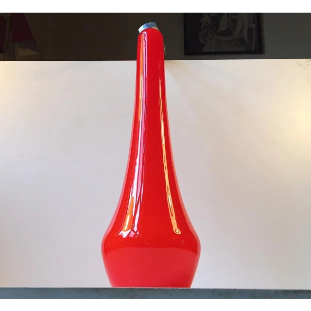 Reminiscent of the designs by Gino Vistosi, this tall organically shaped pendant lamp is made of cased orange glass....