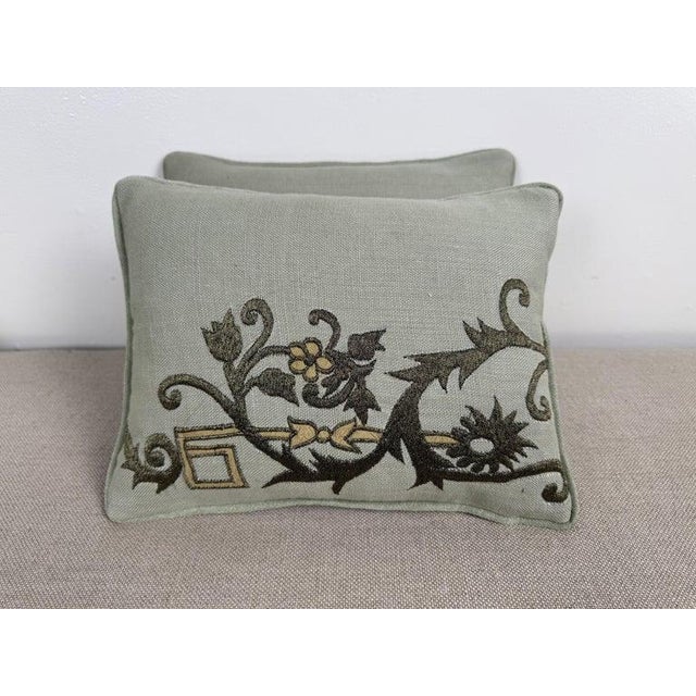 These charming petite pillows are crafted from soft sage-toned linen and feature detailed embroidery by Embroidery Palace....