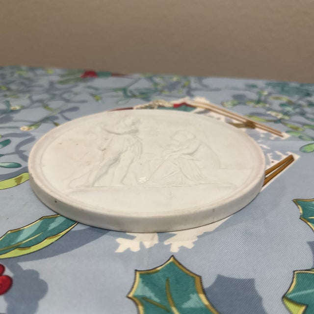 This circular bisque porcelain wall plaque features a Neoclassical bas-relief design. It is part of a celebrated series by...