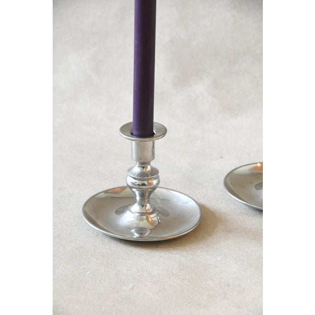 A pair of vintage pewter chambersticks, each with a baluster-turned stem set in a wide, shallow drip pan. Fit them with...