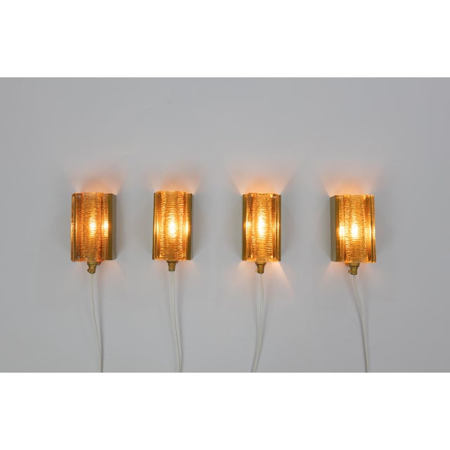 A set of four gold glass and brass Atlantic wall lamps that are produced by Danish lighting manufacturer Vitrika in the...