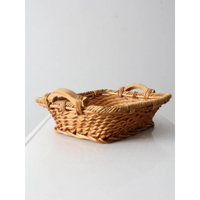 This is a vintage woven basket tray. The decorative serving tray features wooden handles and a wicker basin with braided...