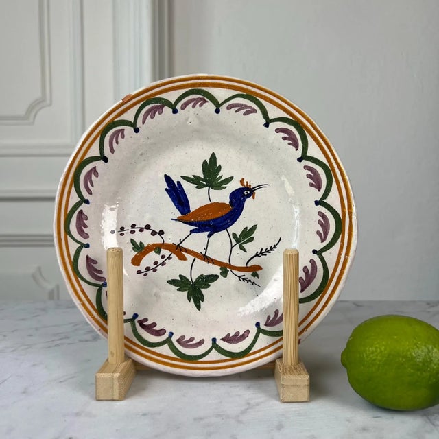 A wonderfully expressive antique French tin-glazed faience plate, hand painted with a stylized exotic bird perched on a...
