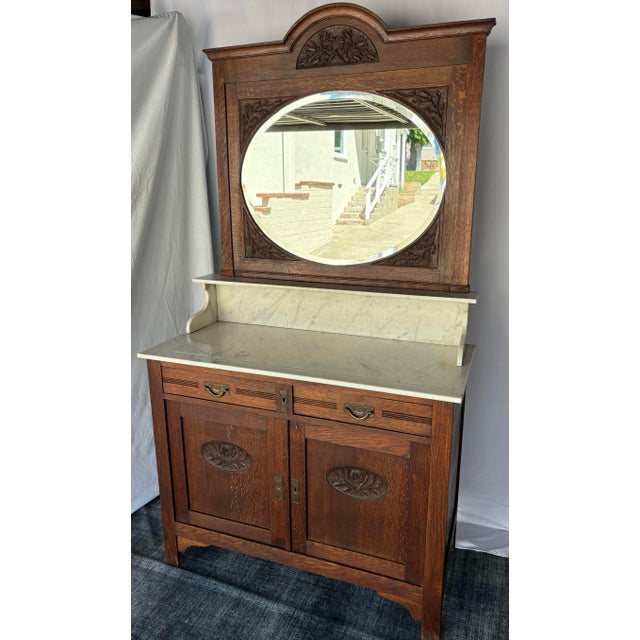 Antique oak washstand / bathroom vanity with a marble top, oval beveled mirror, and floral carvings. Excellent condition....