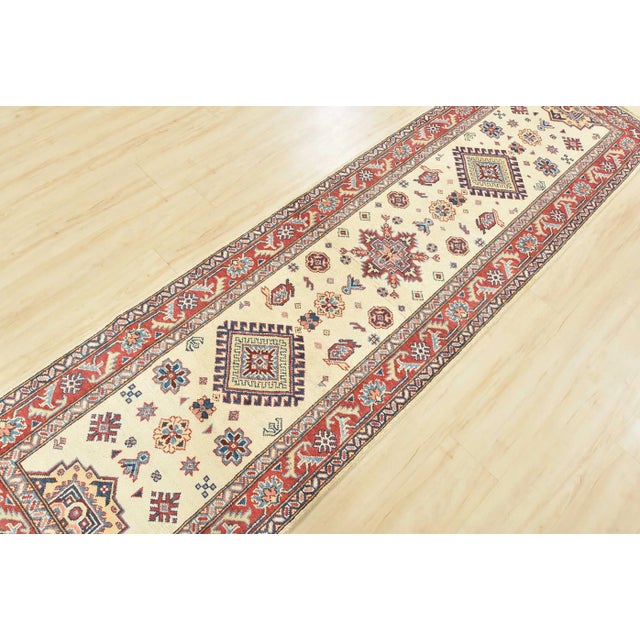This traditional tribal geometric Caucasian Kazak runner is hand-knotted with an all-wool pile on a cotton foundation....