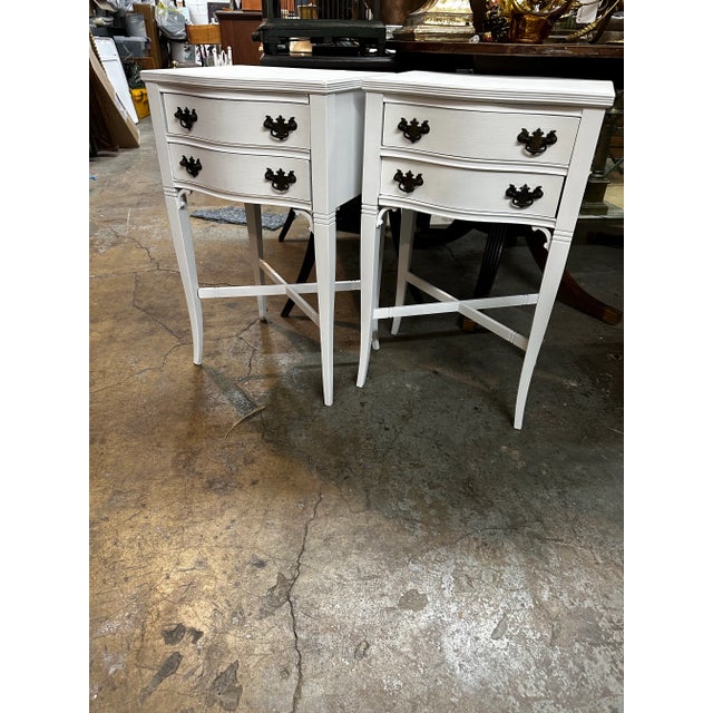 Pair of antique French bombé shaped, crossed legs design off white matte finish and dark bronze hardware two drawers nigh...