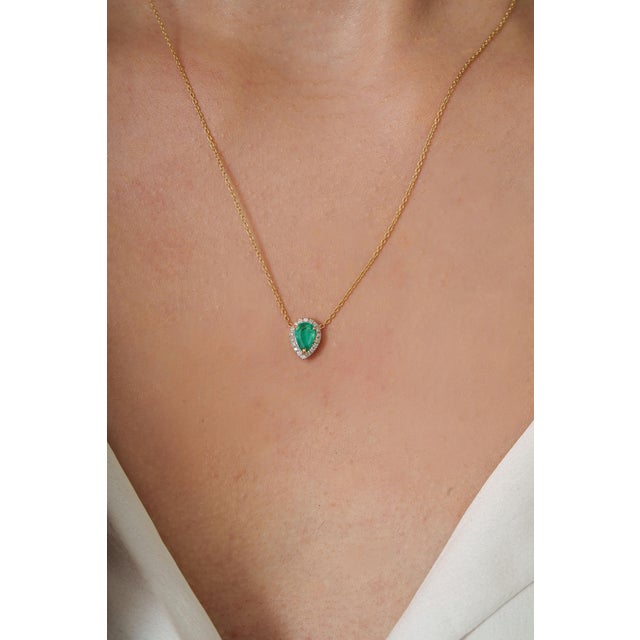 This delicate pendant necklace featuring a 0.33 carat pear-shaped emerald, set in 18K yellow gold. The emerald measuring...