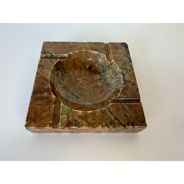 Vintage solid alabaster ashtray featuring a clean square form with a carved round center bowl and four cigarette rests....