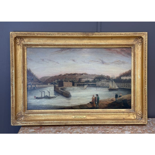 Charming 19th century British School oil on panel painting titled Harbor View. The coastal scene captures a quiet port...