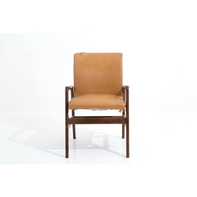 Armchair in brown sky with wooden armrests This piece is attributed to the mentioned designer/maker. It has no attribution...