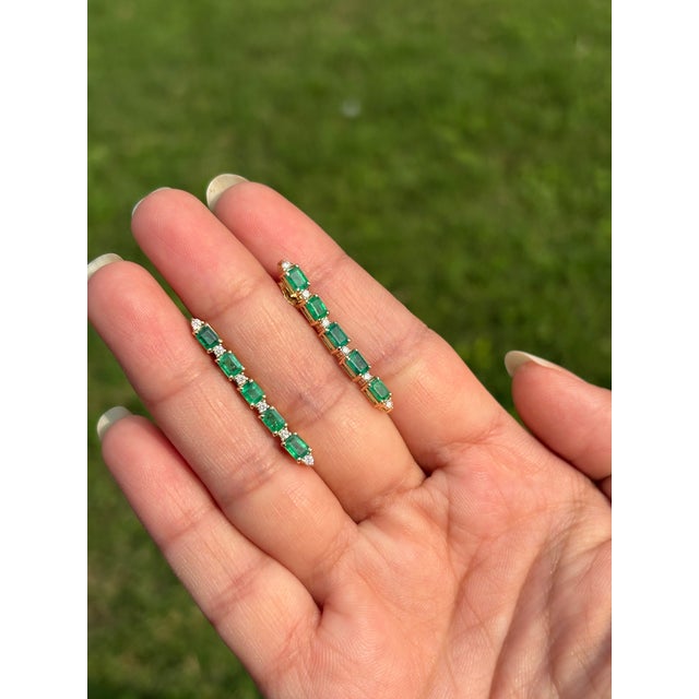 These linear drop earrings feature a 1.87 carat octagon cut emerald and diamond, set in 14k yellow gold. The emeralds...