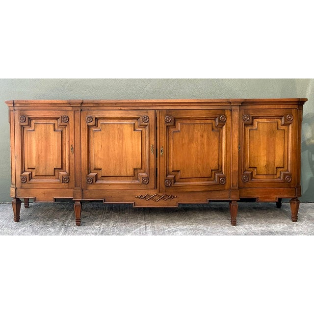 This stately vintage credenza is a masterclass in architectural millwork and classical European design. Crafted from warm-...