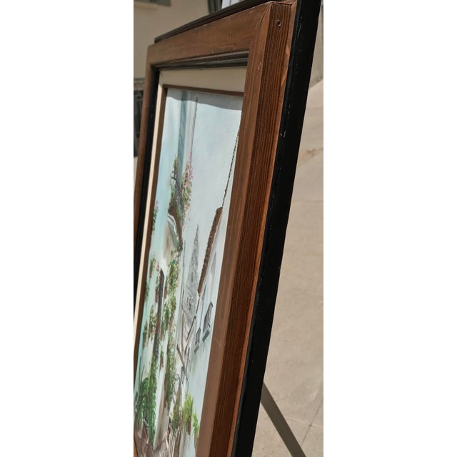 The picturesque painting of a quaint European street is lined with numerous flower pots that adorn the whitewashed walls,...