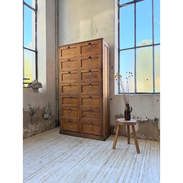 Antique and large 1950s oak drop-front cabinet. comprising 14 drop-front compartments topped with metal shell handles and...