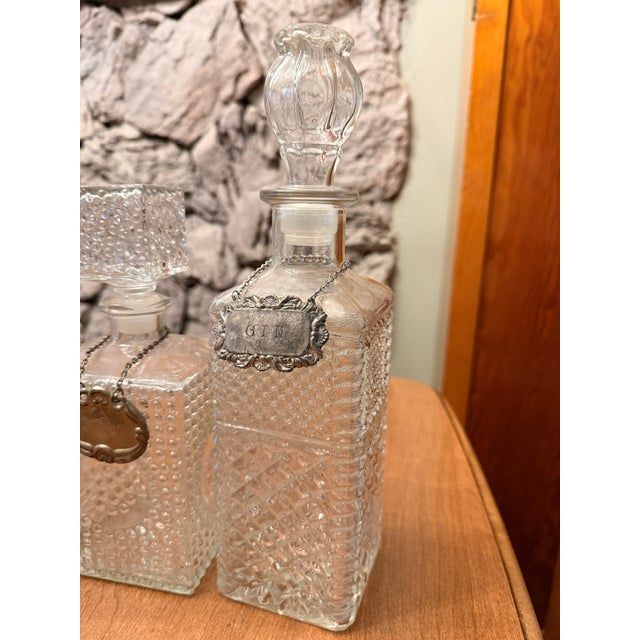 3 crystal liquor decanters with tags and stoppers. Tags are: Bourbon, Whiskey (spelled Whisky) and Gin. All in nice...