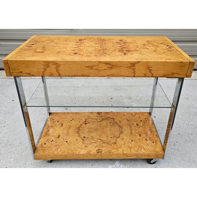 This Milo Baughman Style Mid-Century Modern Burl Wood and Chrome Bar Cart by Lane is a magnificent design that beautifully...