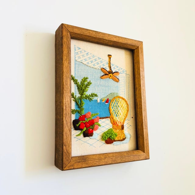 A sweet vintage needlepoint artwork. Features a living room scene with a peacock chair surrounded by houseplants. An open...