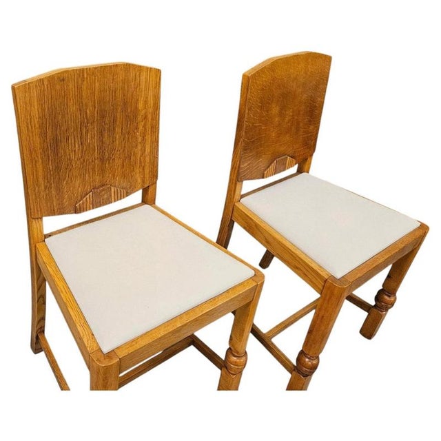 An elegant pair of British Art Deco side chairs, dating to circa 1930, beautifully crafted in oak and distinguished by...