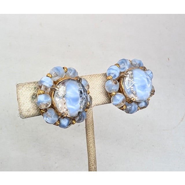 1950s round goldtone baby blue & clear givre round center with faceted bead surround clip earrings. Marked "CARNEGIE" on...