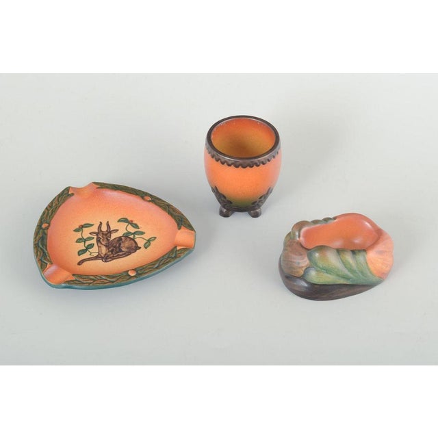 Ipsens enke ashtray, vase and pipe holder. Denmark, circa 1920s–30s. A set of three stoneware pieces with multicolored...