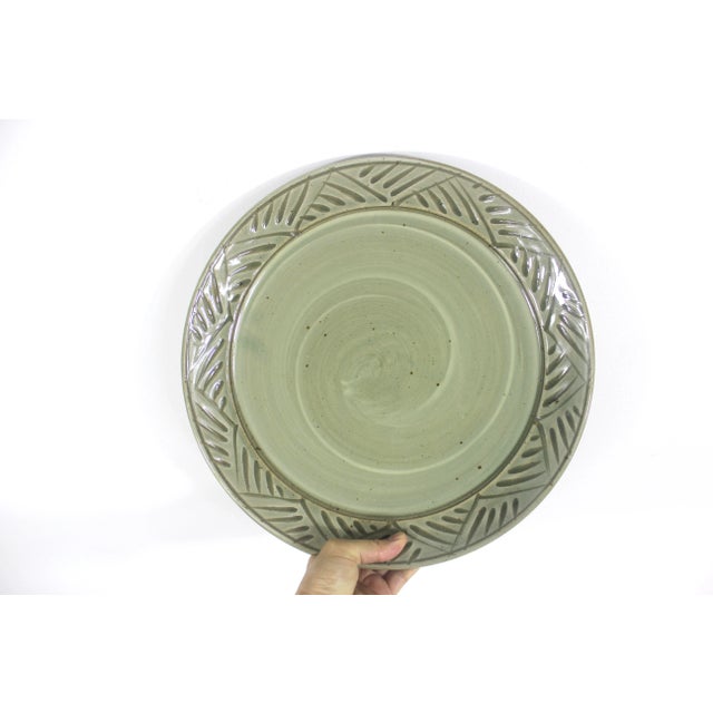 Vintage, signed, speckled green studio pottery platter or very large plate with a carved detail edge. Signed on the...