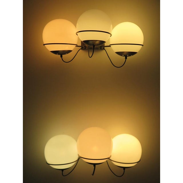 Pair of wall sconces composed of three diffusers produced by Candle with burnished metal frame and opaline glass...