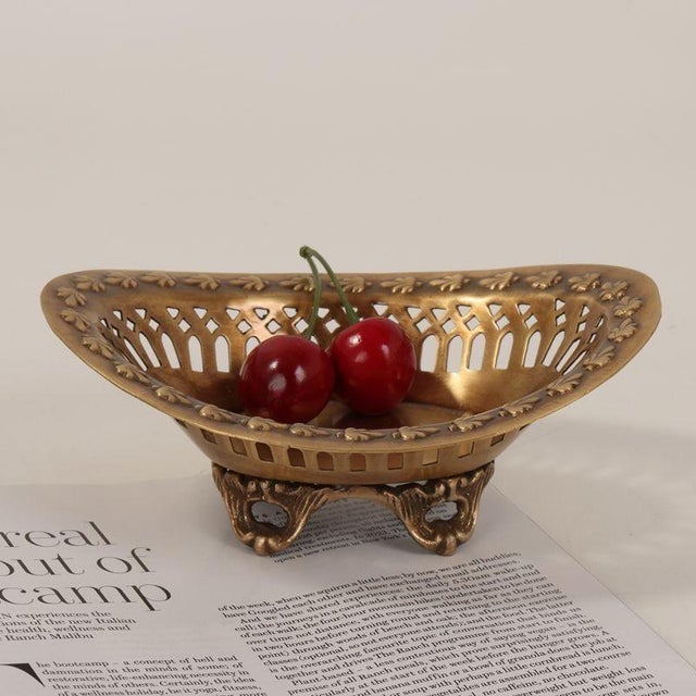 This vintage-inspired dish features a weathered gilded finish (emulating aged brass) with a curved, boat-shaped...