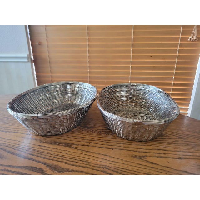 Pair of vintage woven metal baskets featuring a tight crisscross lattice pattern and a bright silver‑tone finish. Their...