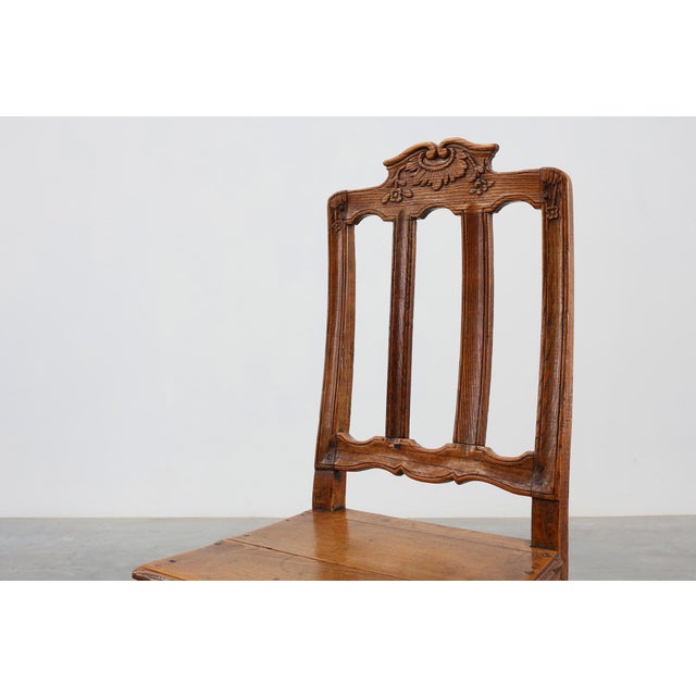 A finely carved oak side chair from 18th‑century France, executed in the Régence style. The chair features a scrolled...