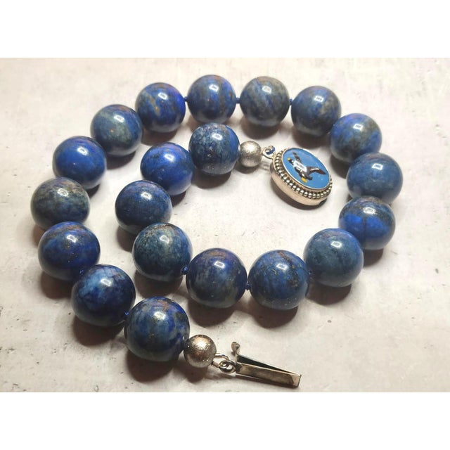 This necklace measures 18 inches (45.7 cm) in length and features smooth, round beads, each 20 mm in size. The lapis...
