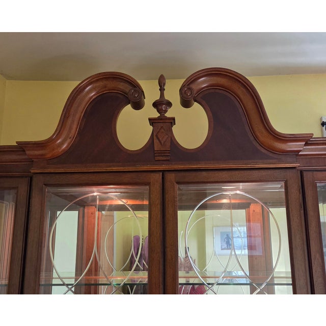 This stately, late 20th-century china cabinet features a swan-neck (broken) pediment with a central finial, multi-pane...