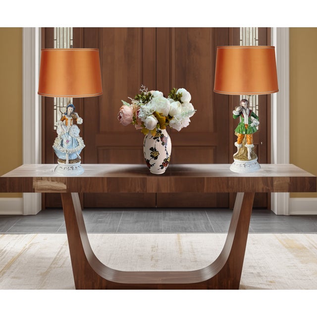 Elegant and highly decorative pair of vintage porcelain figural table lamps featuring a colonial-era courting couple...