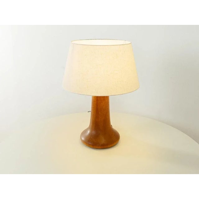Wonderful table lamp from the 1960s. High quality solid wood foot made of teak with a lampshade in cream. Quality...