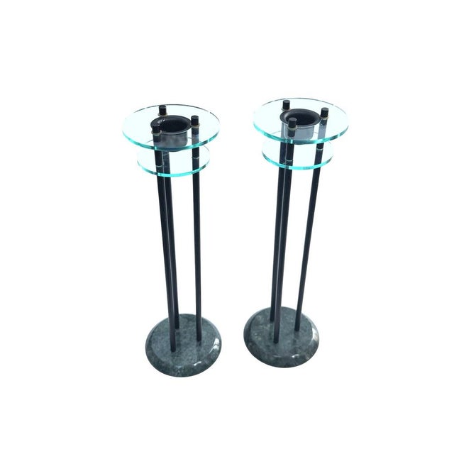 Elegant postmodern candlestick holders featuring green marble bases, sleek black rods, and transparent glass tiers. A...