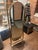 Elegant vintage brass cheval mirror featuring a classic oval glass set within a sculptural freestanding frame. The mirror...