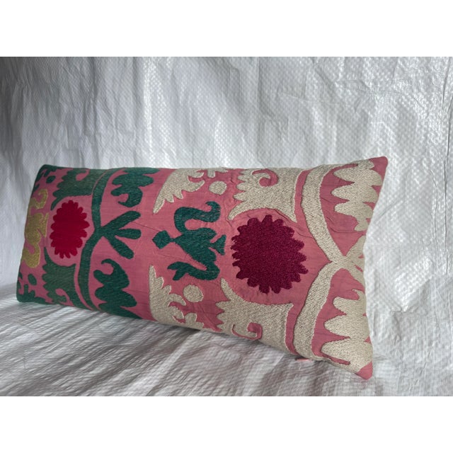 An exquisite antique Suzani lumbar pillow, hand-embroidered in Central Asia during the early 1900s. This elongated pillow...